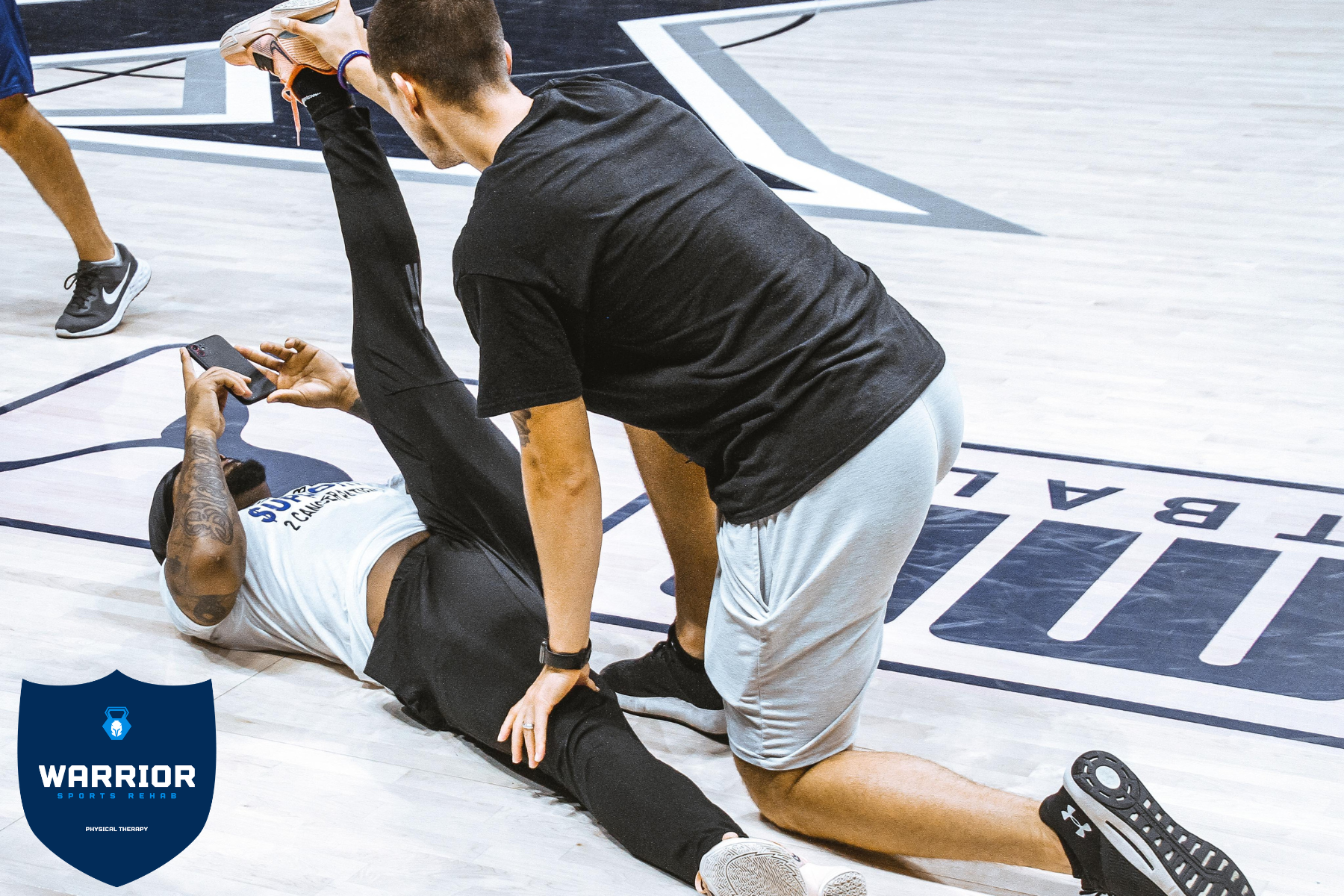 Dr. Tyler Magaha stretching a basketball player courtside